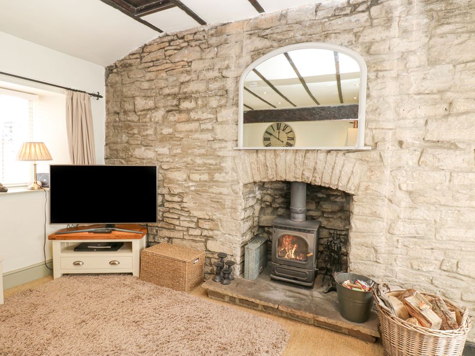 A living room with a fireplace and television at In & Out Cottage Leyburn