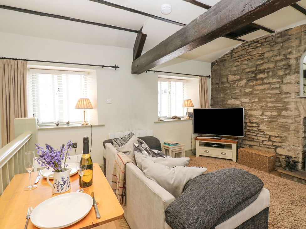 A living room with a tv and dining table at In & Out Cottage in Leyburn