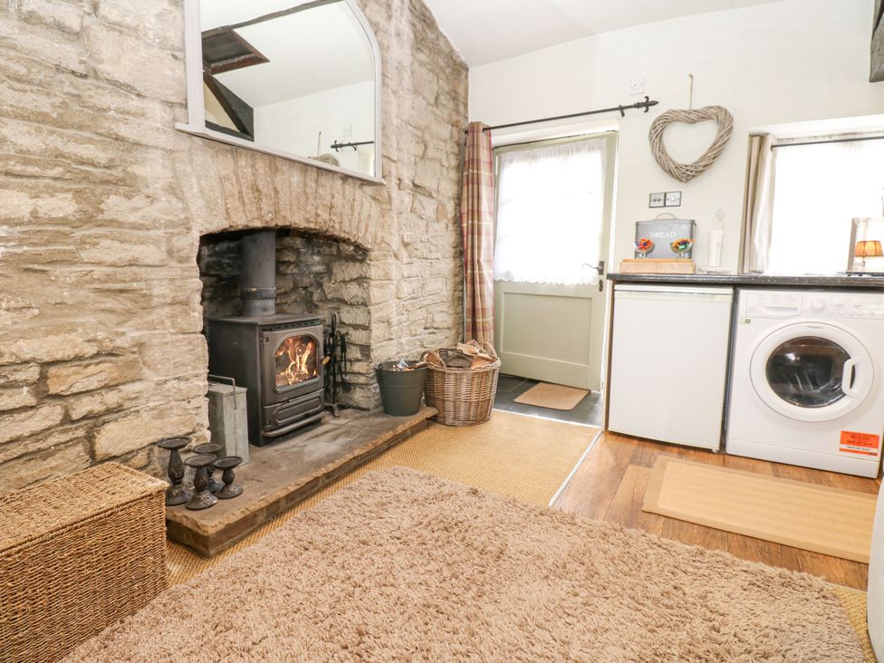 A living room with a wood stove and washing machine at In & Out Cottage Leyburn