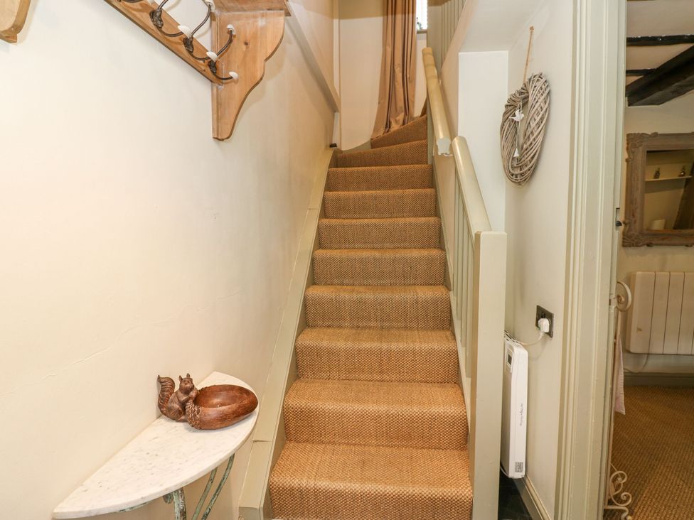 A staircase with a decorative item on a side table at In & Out Cottage Leyburn