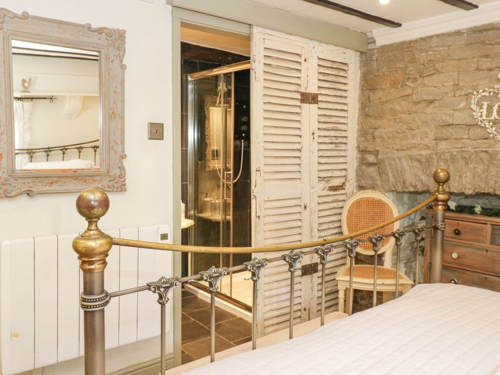 A bedroom with a bed and a shower area at In & Out Cottage Leyburn