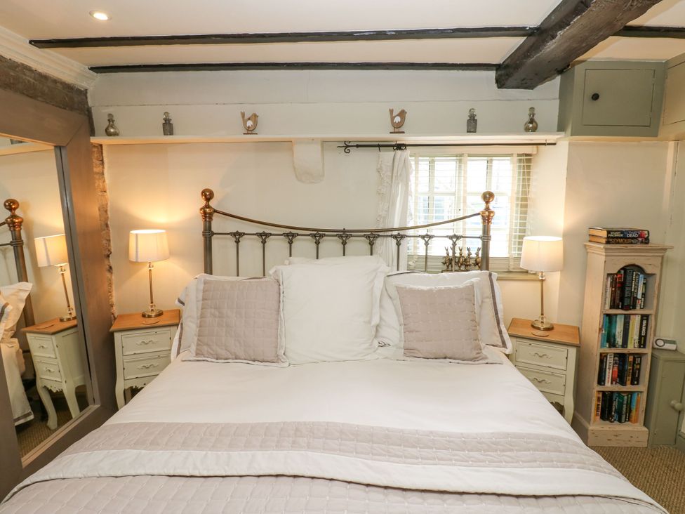 A bedroom with a bed and bookshelf at In & Out Cottage in Leyburn
