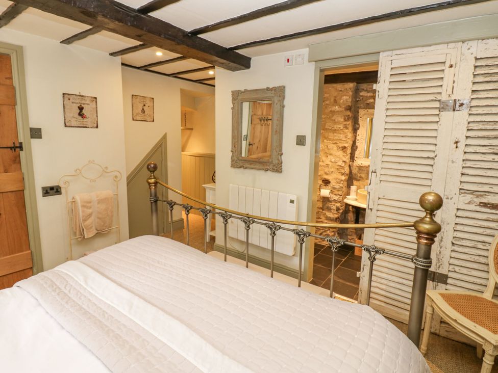 A bedroom with a bed and mirror at In & Out Cottage Leyburn