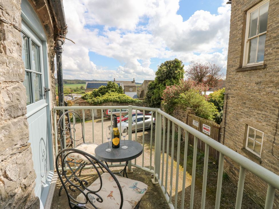 A balcony with a table and chairs at In & Out Cottage in Leyburn