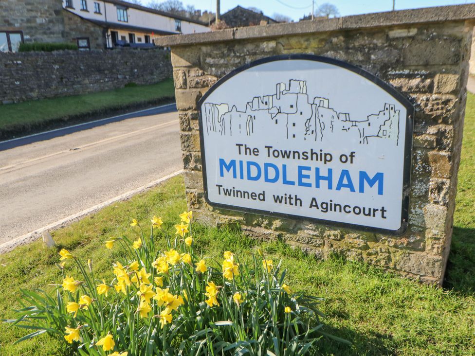 A sign for the Township of Middleham with flowers at the base in Middleham