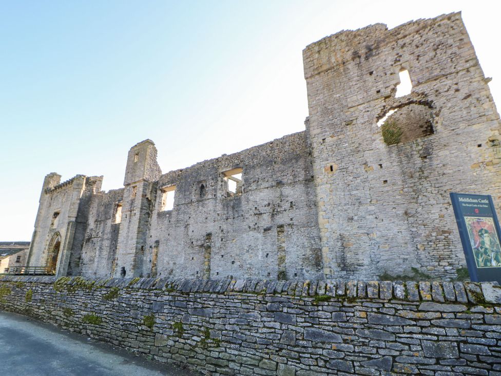A view of castle ruins with a stone wall at Middleham Castle Leyburn