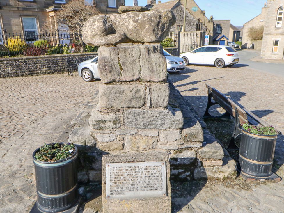A monument with a plaque and benches in an outdoor area at In & Out Cottage Leyburn
