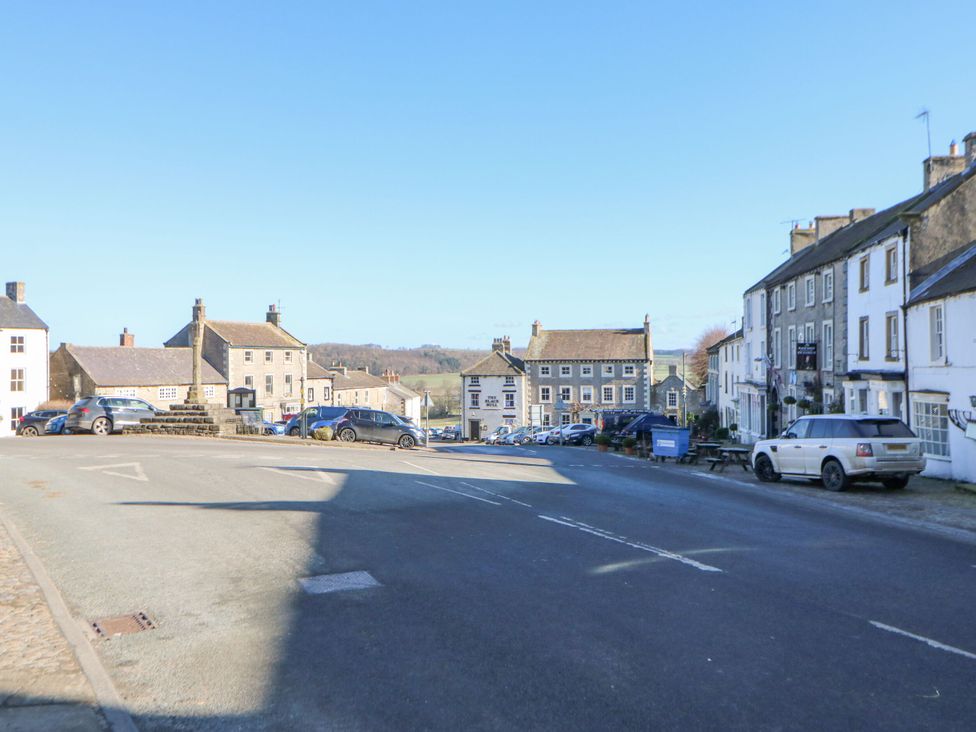 A street view with buildings and parked cars at In & Out Cottage Leyburn