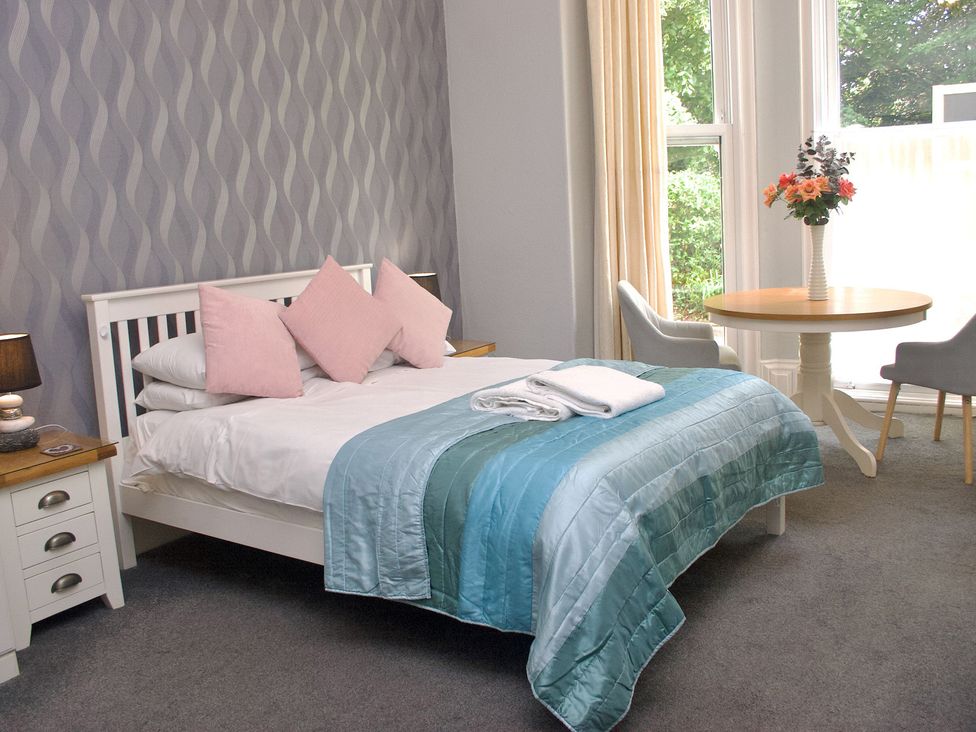A bedroom with a bed and a table at Apartment 1 in Torquay