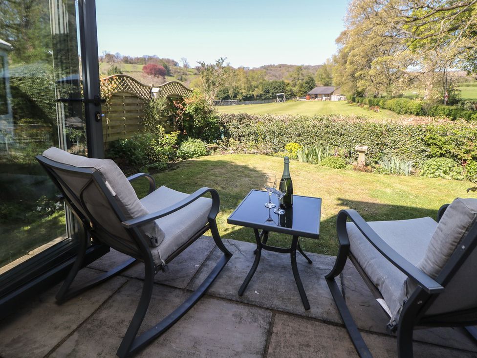 An outdoor space with chairs and a table overlooking a garden at Pine Cottage