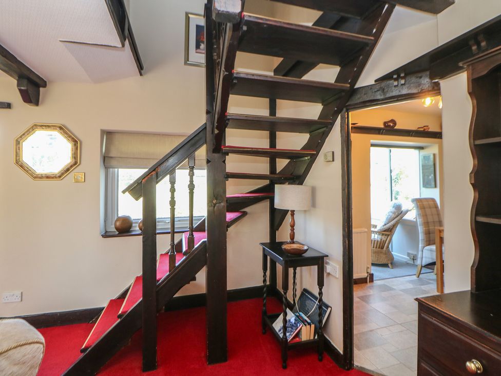 A staircase leading to an upper floor with a table and lamp in a hallway at Pine Cottage