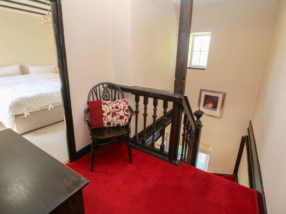 A staircase with a chair and bed visible at Pine Cottage in 
