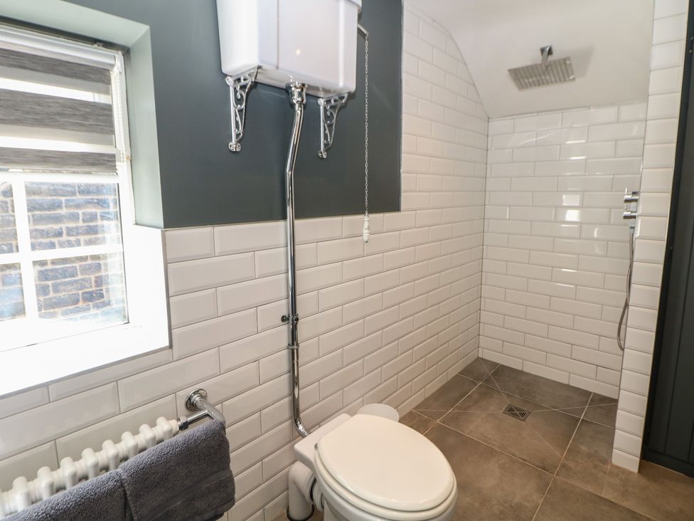A bathroom with a shower, toilet, and towel at Pine Cottage