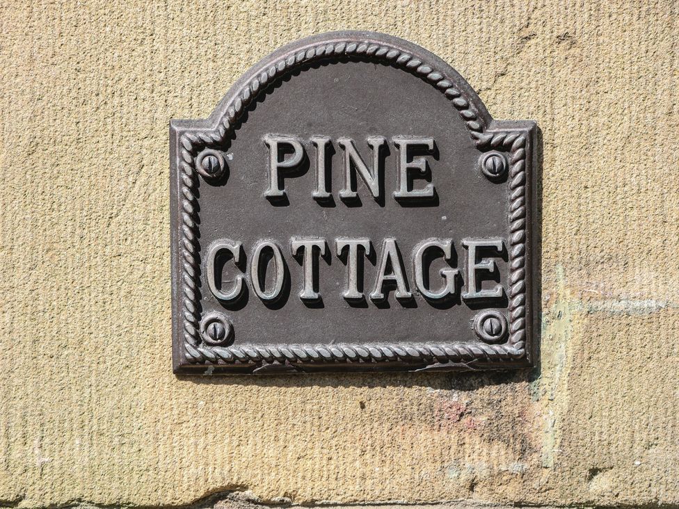 A sign reading Pine Cottage on a wall at Pine Cottage
