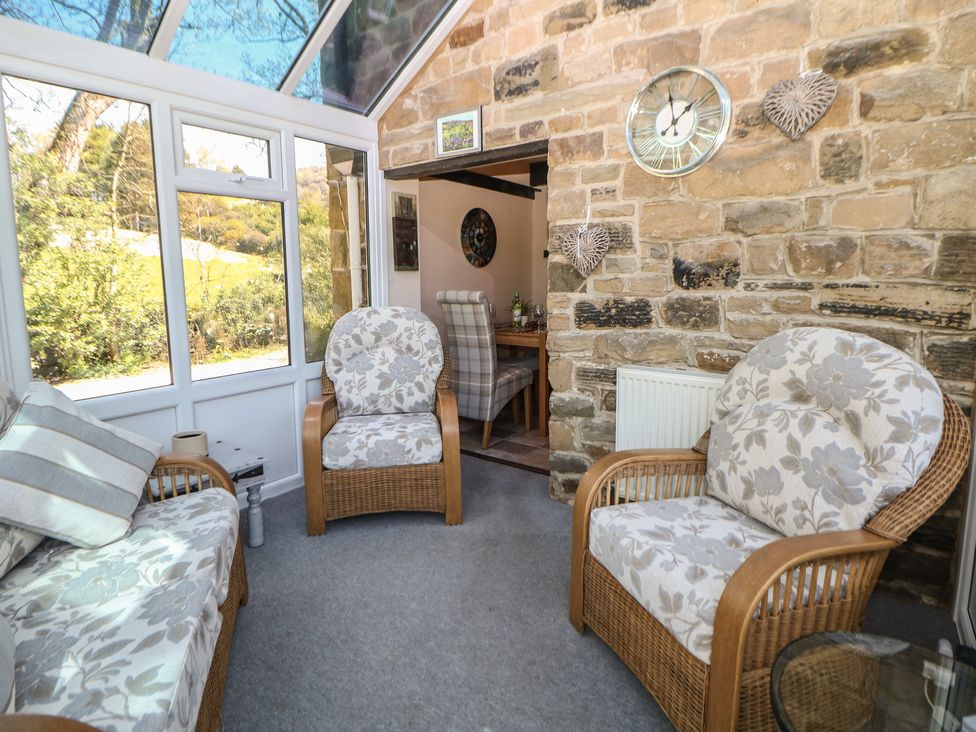 A conservatory with seating area and a dining table at Pine Cottage