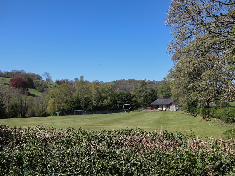 An outdoor area with a field, shed, benches, and trees at Pine Cottage