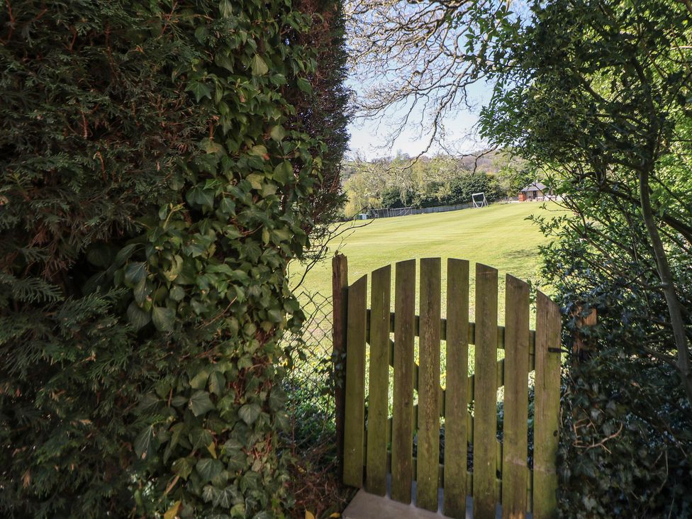 A wooden gate opening to a grass field at Pine Cottage 