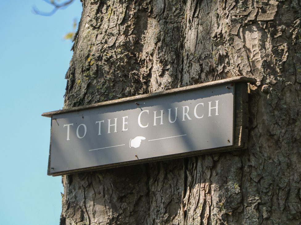 A sign indicating direction to the church on a tree at Pine Cottage