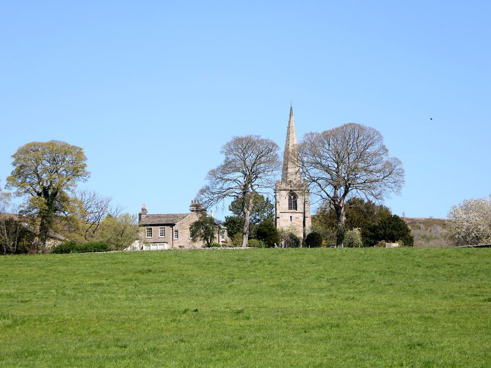 A house and church surrounded by trees in a field at Pine Cottage