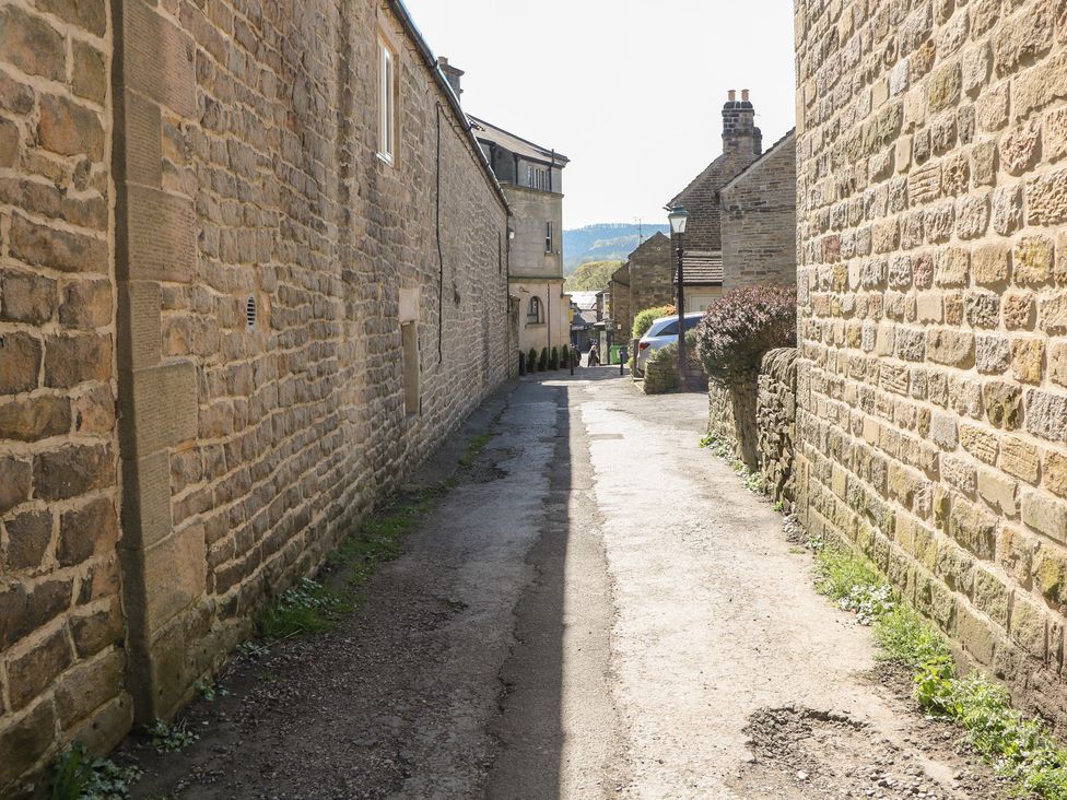 An alley surrounded by stone walls with parked cars at Pine Cottage 