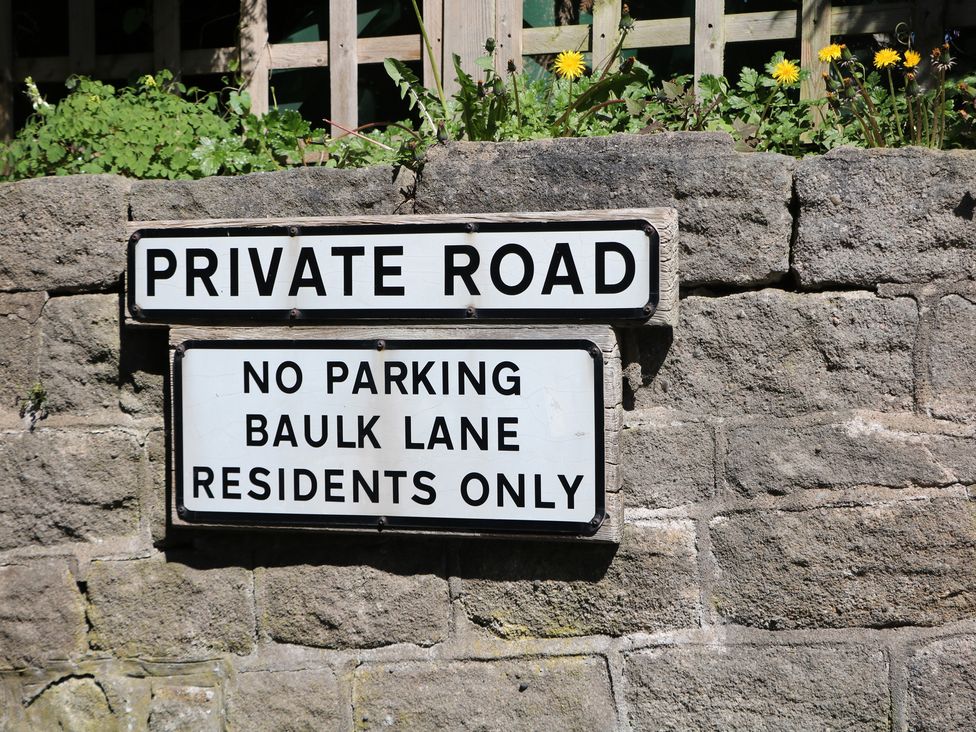 A sign stating private road and parking restrictions at Pine Cottage