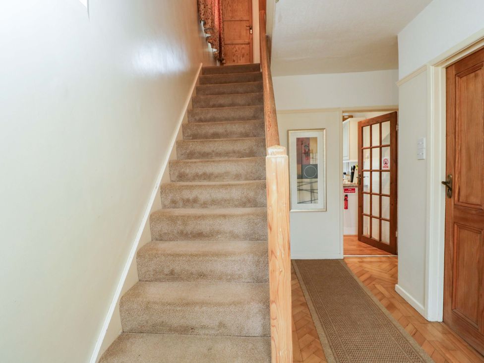 A staircase leading to upper floor with wooden door and kitchen entrance at Highbury in Bath