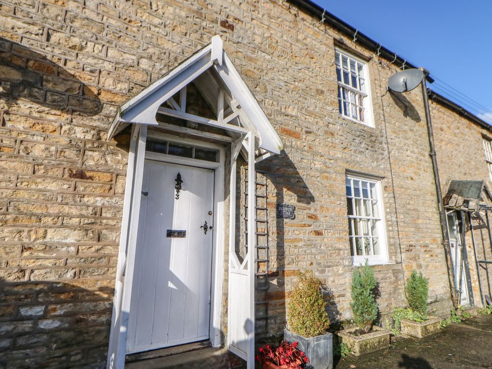 An entrance with a white door and brick wall at Englewood Cottage in Hexham