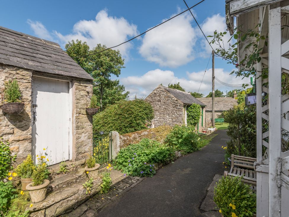 A pathway with stone buildings and garden plants at Englewood Cottage in Allenheads