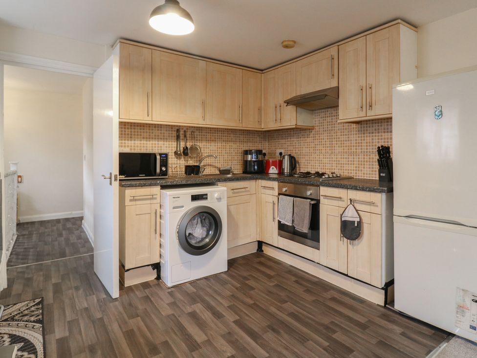 A kitchen with cabinets, appliances and washing machine at Peckhamsbest Suite in London