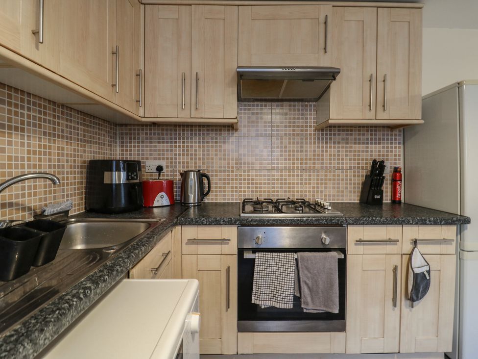 A kitchen with cabinets, stove, sink, and small appliances at Peckhamsbest Suite in London