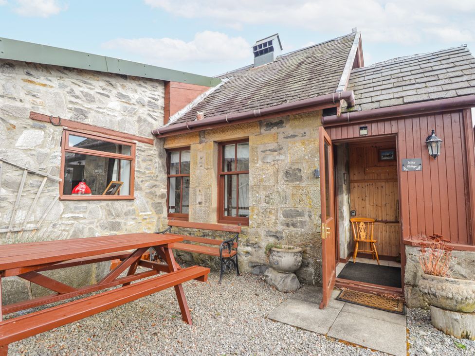 An outdoor area with a wooden table and benches at Islay Cottage Kincraig