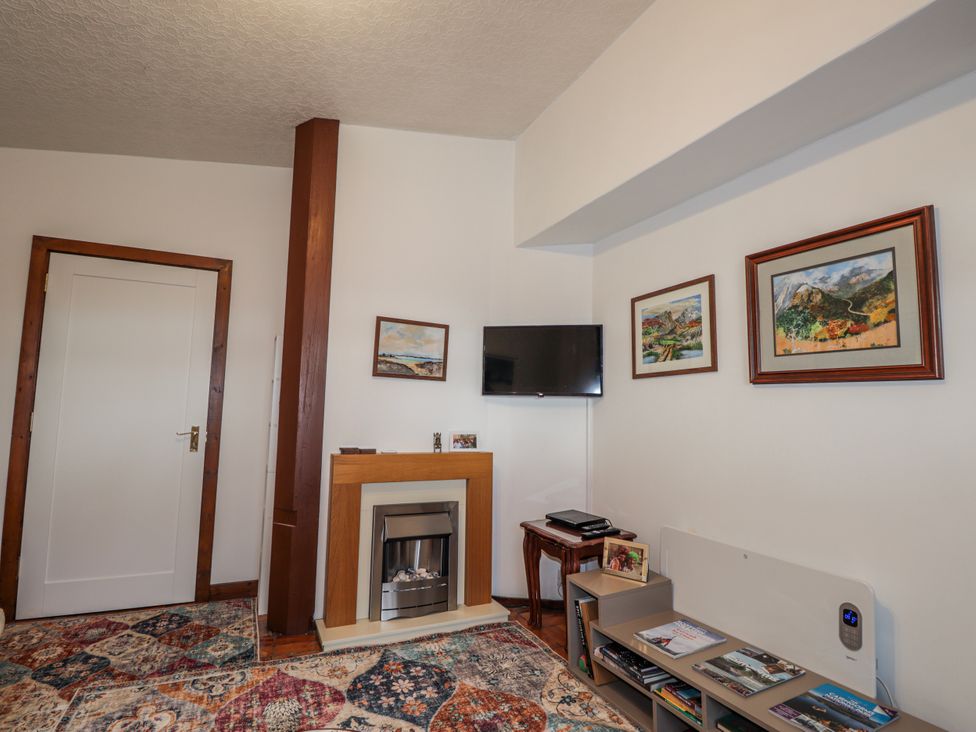 A living room with a fireplace and television at Islay Cottage in Kincraig
