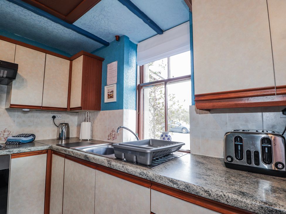 A kitchen with sink, cabinets, and appliances at Islay Cottage in Kincraig