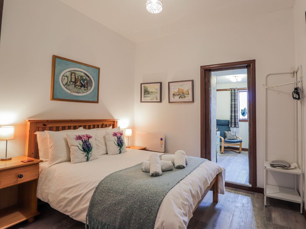 A bedroom with a bed and artwork on the walls at Islay Cottage in Kincraig