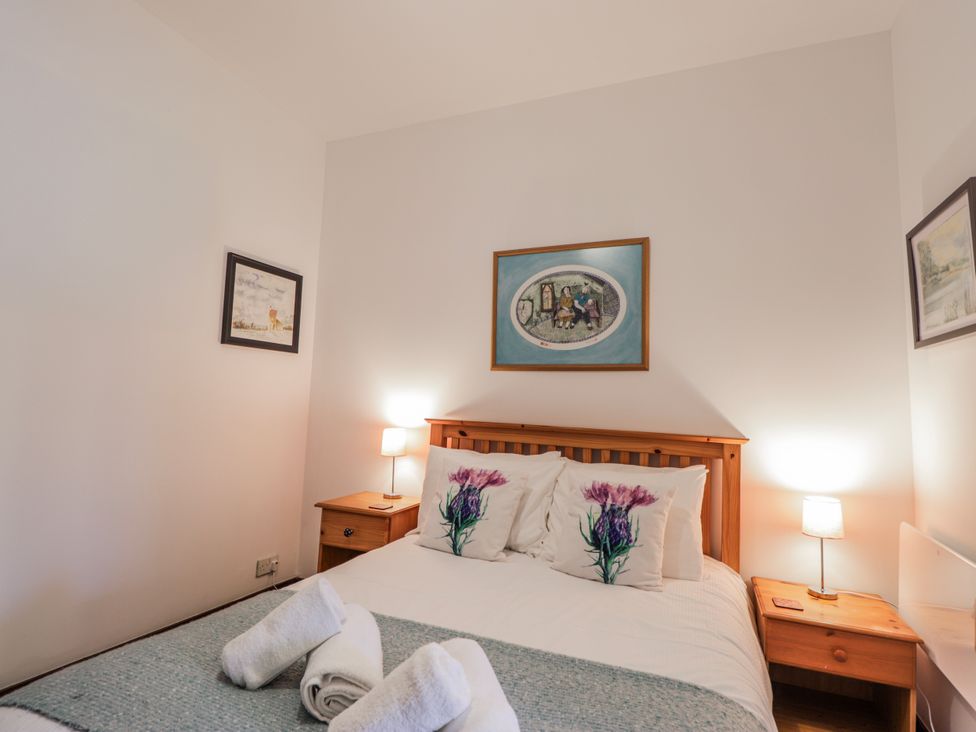 A bedroom with a bed and bedside tables at Islay Cottage in Kincraig