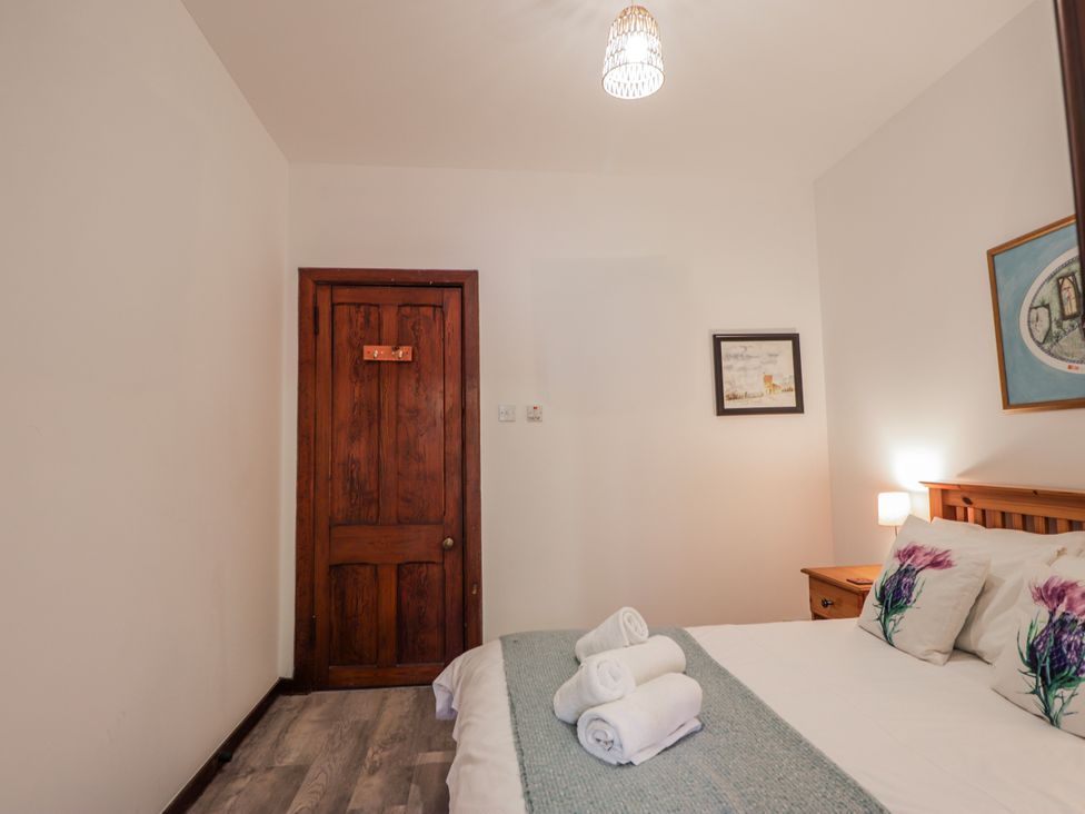A bedroom with a bed and decorative items at Islay Cottage Kincraig
