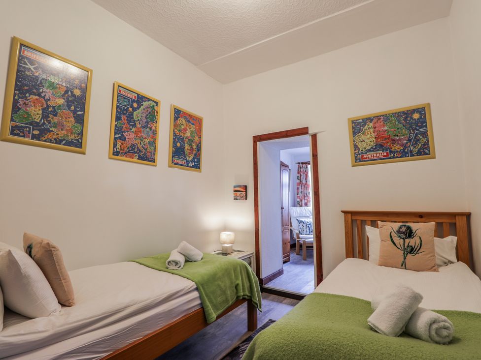 A bedroom with two beds and maps on the wall at Islay Cottage in Kincraig