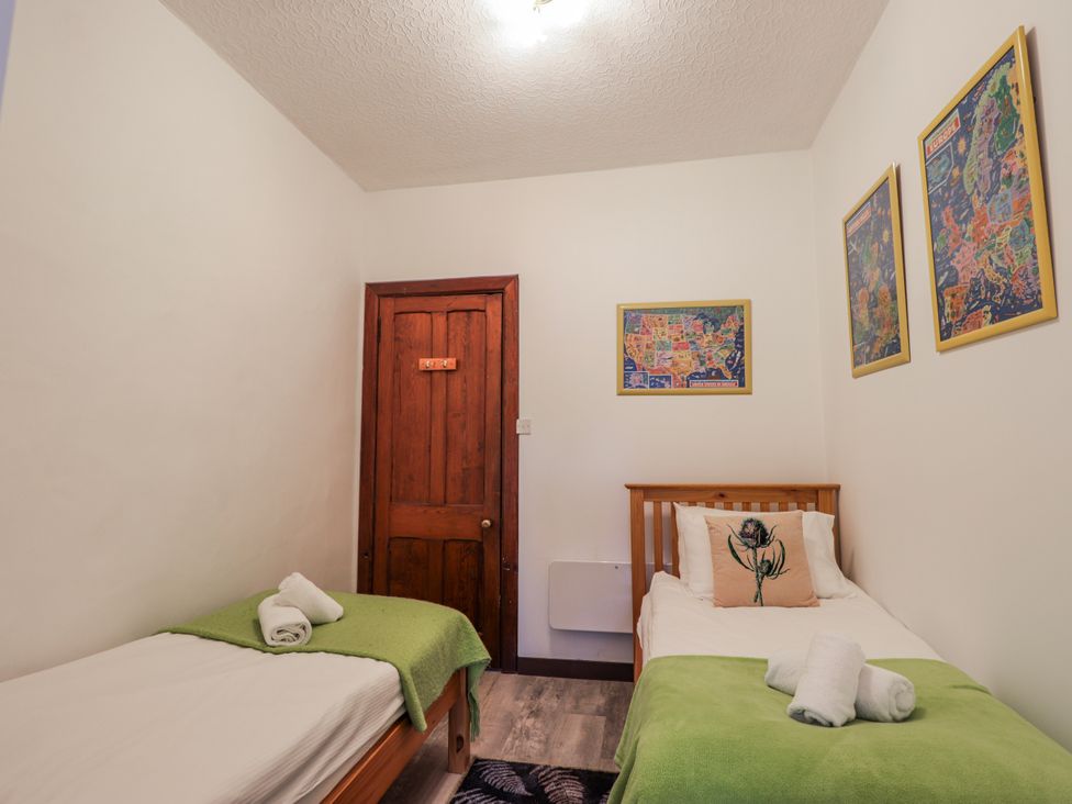 A bedroom with two beds and a door at Islay Cottage Kincraig
