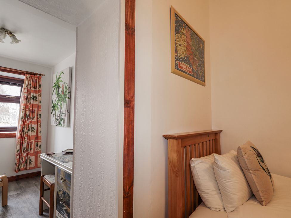 A bedroom with a bed and a desk at Islay Cottage in Kincraig