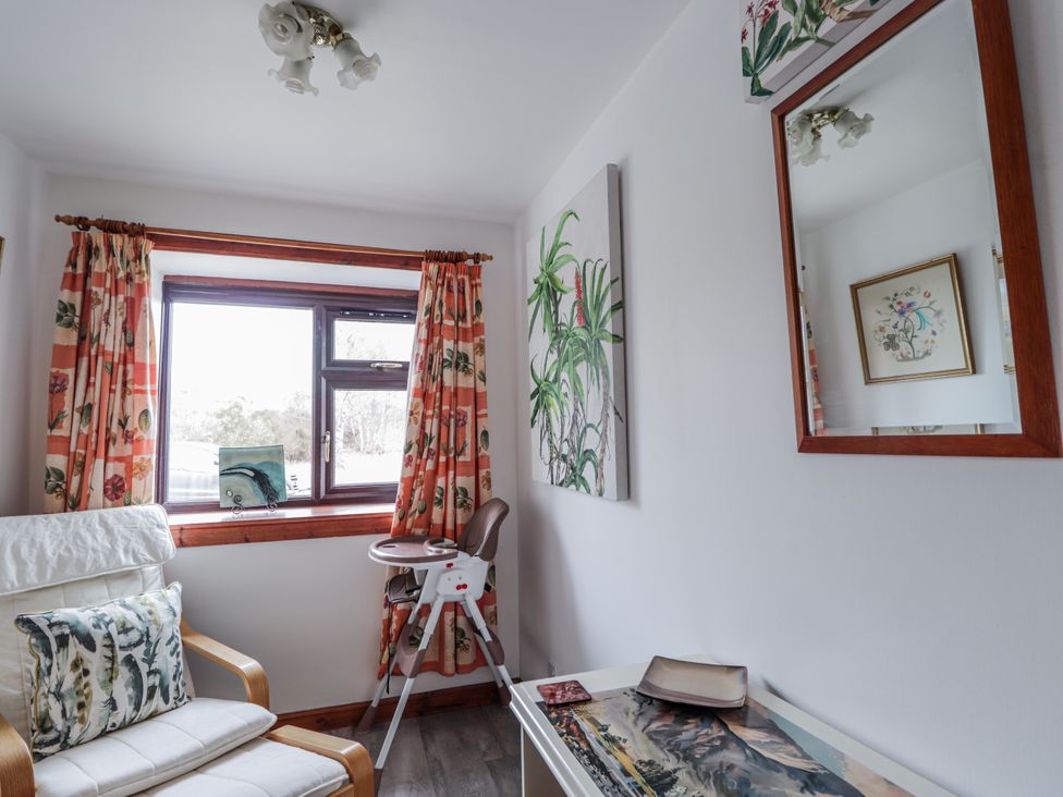 A living room with a window, chair, and painting at Islay Cottage in Kincraig