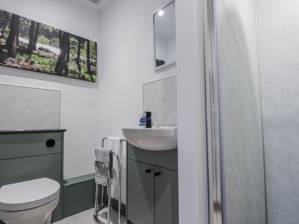 A bathroom with a toilet, wash basin, and shower at Islay Cottage in Kincraig