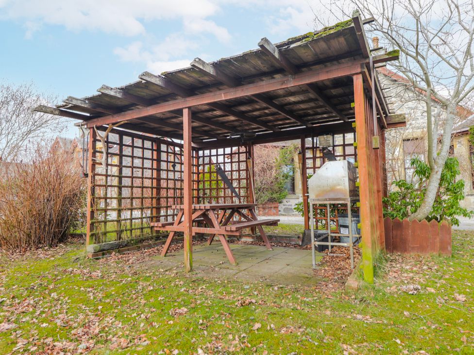 A wooden pergola with a table and benches at Islay Cottage Kincraig