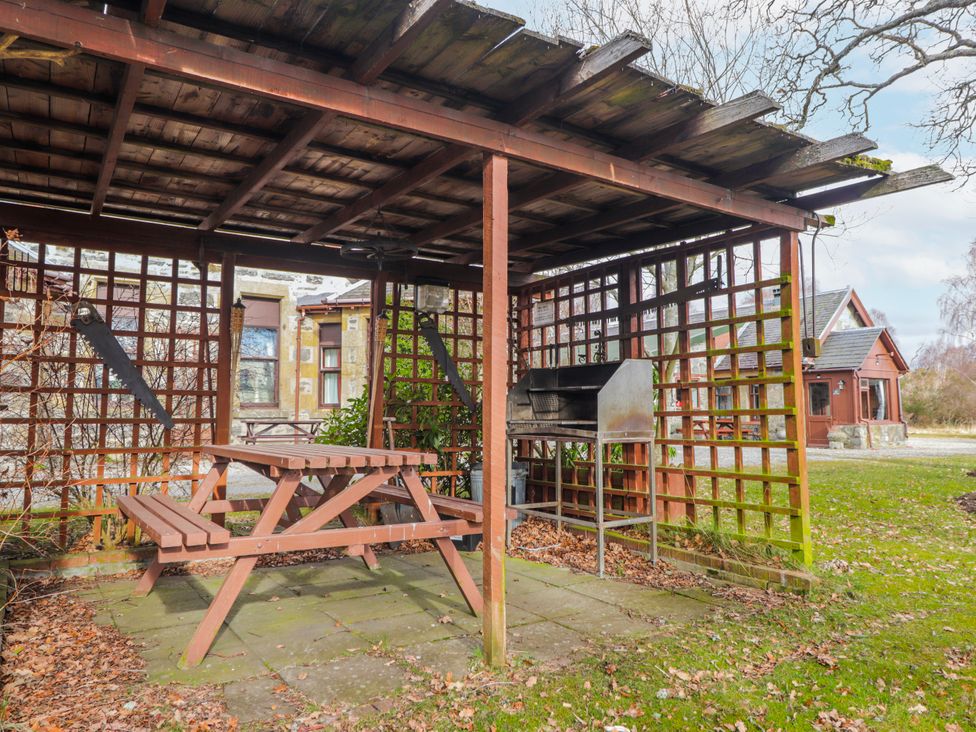 An outdoor dining area with a table and grill at Islay Cottage Kincraig