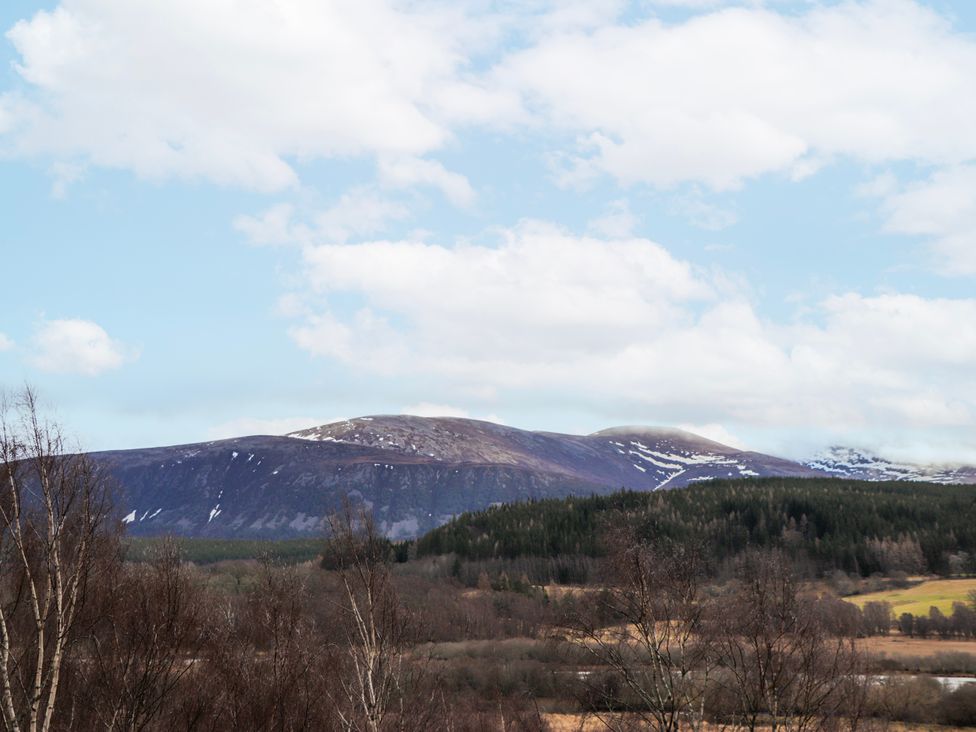 A view of mountains with snow and trees at Islay Cottage in Kincraig