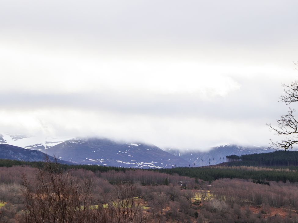 A view of mountains with clouds and trees at Islay Cottage Kincraig