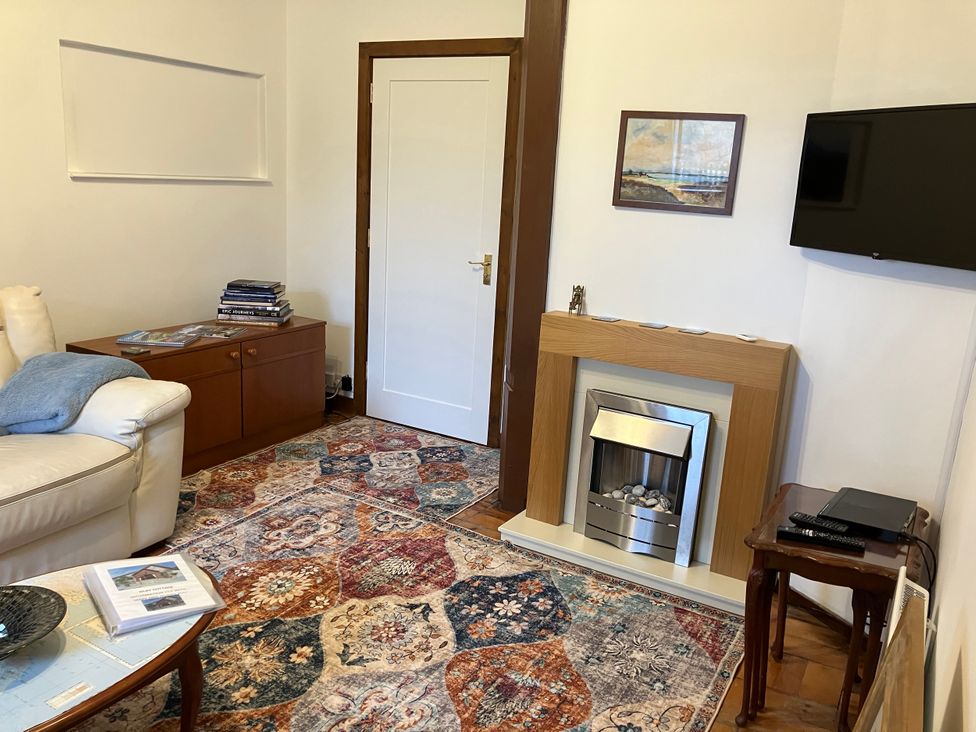 A living room with a sofa and fireplace at Islay Cottage in Kincraig