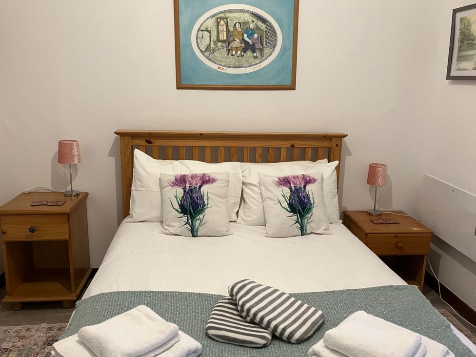A bedroom with a bed and bedside tables at Islay Cottage in Kincraig
