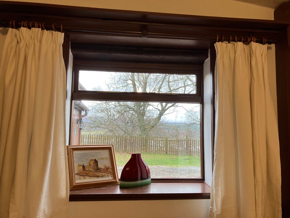 A window with curtains and decorations at Islay Cottage in Kincraig