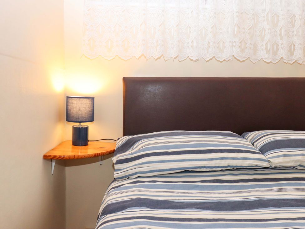 A bedroom with a bed and bedside lamp at Flat 1 Lee Cliff Park in Dawlish Warren