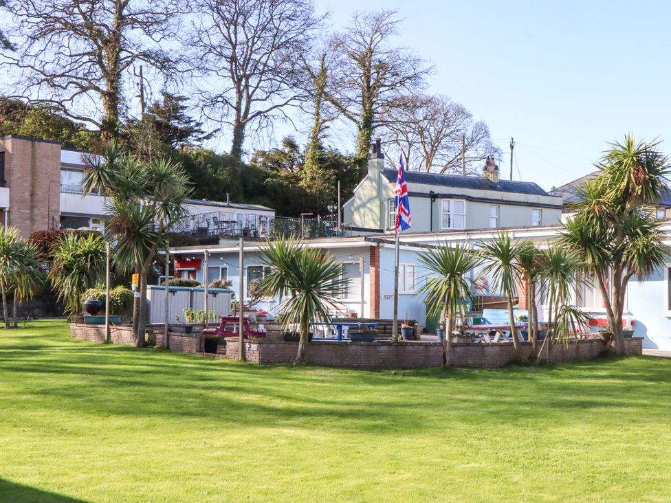 A garden area with palm trees and a building at Flat 1 Lee Cliff Park in Dawlish Warren